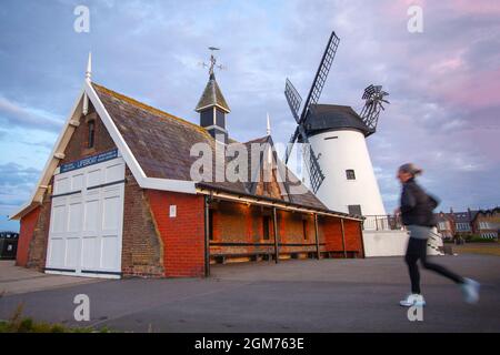 Lytham St. Annes. UK Wetter: 17. September 2021. Wetter in Großbritannien: Sonniger, kühler Start in den Tag mit leichten Winden, während die Anwohner an der Strandpromenade leichte Übungen machen. Windmühlen sind seit Hunderten von Jahren in der Geschichte Lythams zu finden. Im Jahr 1805 suchte Richard Cookson nach einem Grundstück, auf dem ‘windige milne’ gebaut werden sollte, und erhielt einen Mietvertrag von The Squire. Später, im Jahr 1860, als die prestigeträchtigen Häuser in der Gegend gebaut wurden, sahen die Bewohner die Windmühle als eine „industrielle Belästigung“ an; MediaWorldImages/AlamyLiveNews Stockfoto