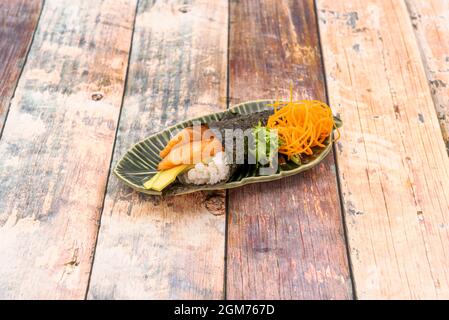 Norwegisches Lachs-Temaki-Sushi mit japanischem Reis, Reisessig, reifer Avocado und Nori-Algen-Kegel auf Holztisch Stockfoto