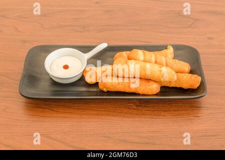 Ration von köstlichen tequeños gefüllt mit Käse gebraten mit Mayonnaise-Sauce auf Holztisch Stockfoto