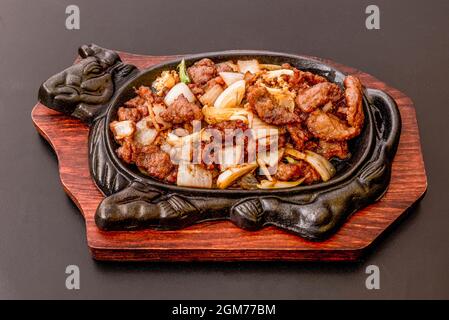 Traditionelles europäisches chinesisches Restaurant mit Rindereintopf und Zwiebeln, serviert auf einer kochenden gusseisernen Grillplatte Stockfoto