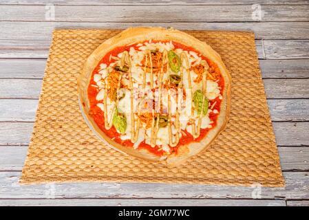 Tex-Mex-Pizza-Rezept mit Guacamole, Tinga-Hühnerfleisch und jalapeños mit Mozzarella-Käse mit Tomaten und Kichererbsenmehl-Teig Stockfoto