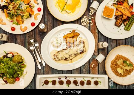 Typische Gerichte und Salate der spanischen Gastronomie, Ochsenschwanzkroketten, Honigreis, Pfeffersirloin, gegrillter Lachs mit Gemüse, Salat mit Walnüssen, Stockfoto