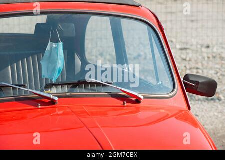 Chirurgische Gesichtsmaske, die an einem alten Fiat 500 hängen kann Stockfoto