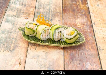 Uramaki sapporo-Rolle, umgeben von Gurkenscheiben und gefüllt mit flambiertem Lachs und Mango Stockfoto
