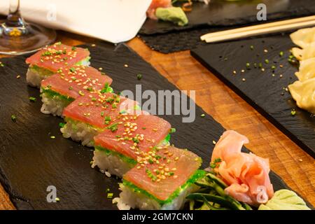 Sushi-Tacos mit Thunfisch-Scheiben, Masago-Rogen, Sesamsamen und gehacktem Schnittlauch mit Ginseng auf schwarzem Schiefer Stockfoto