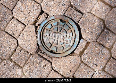 Eine Nahaufnahme eines Metall-, Stahl-, Eisen-Runde Wasserschachtels, Kappe in einem gemauerten Bürgersteig. In Arlington, Virginia. Stockfoto