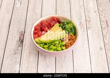 Poke eine Schüssel roten Thunfisch in Würfel, Scheiben reifer Avocado, edamame Bohnen, knusprige Zwiebel, Wakame-Algensalat und weiße Reisbasis Stockfoto