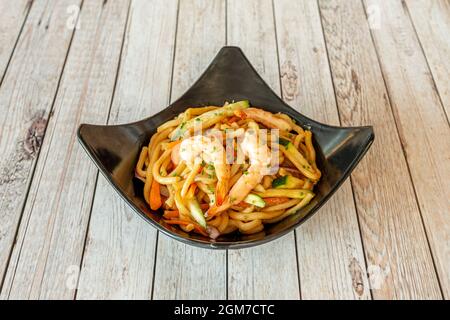 Schüssel mit udon-Nudeln mit gekochten Garnelen und Wok-sautiertem Gemüse Stockfoto