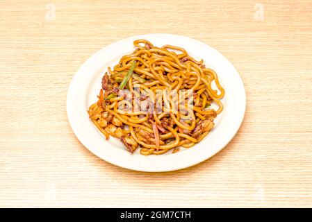 Gebratene udon-Nudeln mit Hühnchen und Gemüse in einem Wok mit Sojasauce anbraten Stockfoto