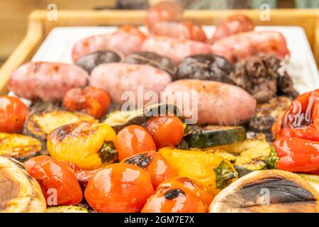 Chorizos, Würstchen, Gemüse und Pilze werden an einem Sommergrilletag auf dem Grill zubereitet Stockfoto