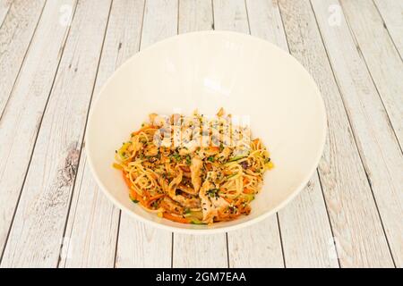 Nudeln mit Hühnchen, Gemüse und Samen mit Yakisoba-Sauce in einer weißen Schüssel anbraten Stockfoto