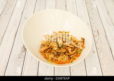 Hühnernudeln Yakisoba, die mit Gemüse und Mohn, Sesam und gehacktem Schnittlauch auf einem weißen Tisch anbraten. Stockfoto