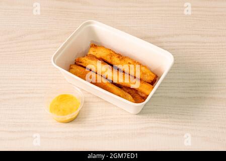 Gebratene Cassava-Streifen in einem Lieferbehälter mit süßer Sauce Stockfoto