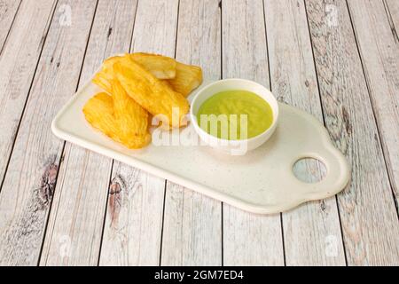 Tablett mit leckeren gebratenen Yucca mit grüner Sauce in eine kleine weiße Schüssel zu tauchen Stockfoto