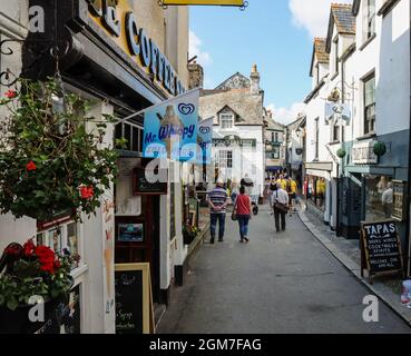 Die engen Straßen, wie die hier zu sehende Higher Market Street und die Gassen in East Looe, Cornwall, beherbergen eine Vielzahl von Geschäften, Cafés und Pubs. A journ Stockfoto