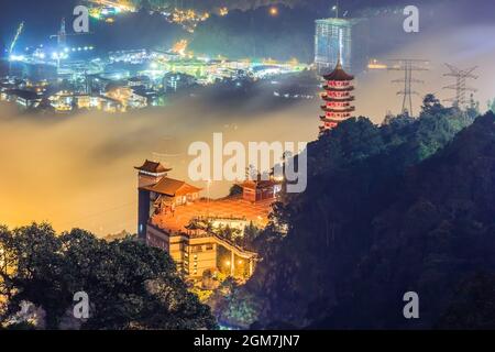 Chin Swee Cave Temple in Genting Highlands in der Abenddämmerung mit Blick auf den Aussichtspunkt des Themenpark-Hotels im Hintergrund Stockfoto