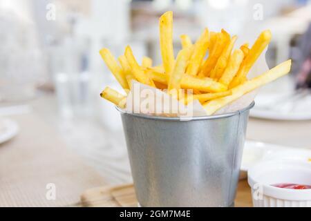 King Pommes, eingewickelt mit einem Papier in einem kleinen Eimer aus Edelstahl auf einem Holztisch, Selective Focus Stockfoto