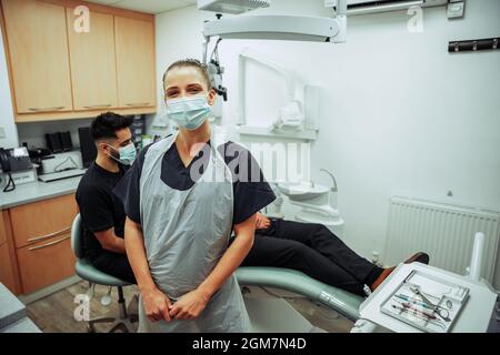 Kaukasische Krankenschwester, die in der Arztpraxis steht und sich mit einem männlichen Kunden beraten kann Stockfoto