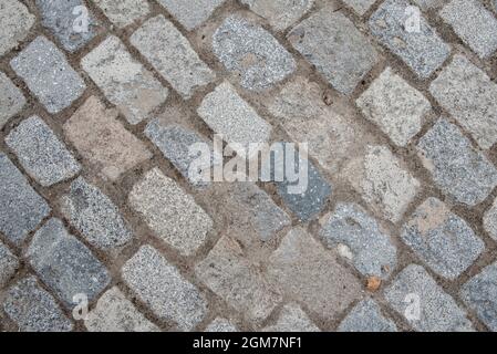 Pflastersteine einer Straße, die auf der Diagonale des Rahmens gepflastert ist. Vektor Granit Textur Hintergrund Stockfoto