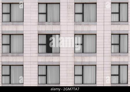 Weiße Marmorgranitfassade und mehrere Fenster mit schwarzen Metallrahmen geschlossen Stockfoto