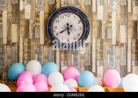 Vintage Uhr hängt auf der Holzwand Hintergrund mit bunten Luftballons Stockfoto