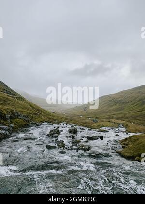 Färöer-Inseln, Vagar, Gebirgsfluss. Nordische Landschaft, braune Felder und Hügel Stockfoto