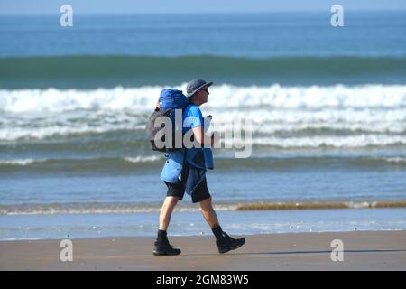 Ein Spaziergang entlang der Gezeitenlinie über einen von einer Brandung gesäumten Strand von Rhossili nach Llangenith am Gower in Wales Stockfoto