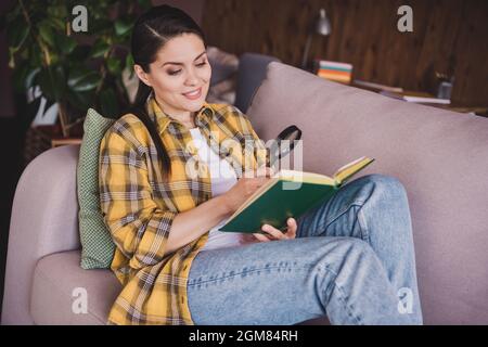 Foto von charmanten glücklich entspannt Frau Look Buch halten Hand Lupe Glas drinnen im Haus Wohnung Stockfoto