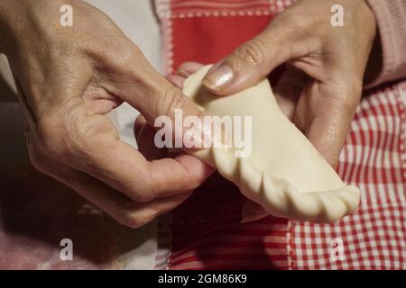 Frauenhand bereitet argentinische Repulgue Empanadas vor Stockfoto