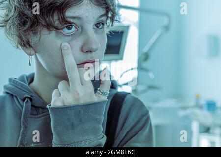 Teenager-Mädchen mit dunklen Kreisen unter ihren Augen und blasses Gesicht schaut im Spiegel auf ihre Reflexion und sieht. Konzept der Multiple-Persönlichkeit-Störung, Mora Stockfoto