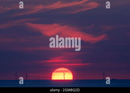 Offshore-Windpark in der Ostsee im Licht der untergehenden Sonne mit Schiffen Stockfoto