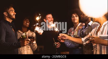 Glückliche junge Freunde, die Spaß mit Wunderkerzen Feuerwerk beim Trinken von Cocktails auf der Terrasse des Hauses Party - Jugend Menschen Lifestyle und Urlaub Konzept Stockfoto