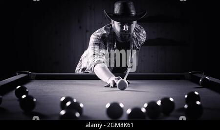 Ein Mann mit einem Bart spielt eine große Billard. Partei in 12-Fuß-Pool. Billard im Club Spiel für Männer. Ein Mann mit einer Cue bricht die Pyramide. Stockfoto