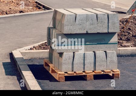 Unterflurstein auf der Baustelle. Palette mit Einem Stapel Beton-Bordstein. Straßenreparaturen. Stockfoto