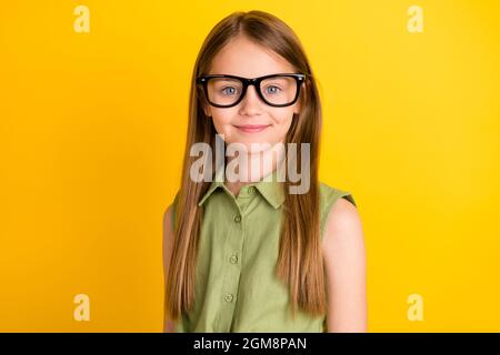 Foto Porträt Schulmädchen tragen grüne Hemd Brille lächelnd isoliert leuchtend gelbe Farbe Hintergrund Stockfoto