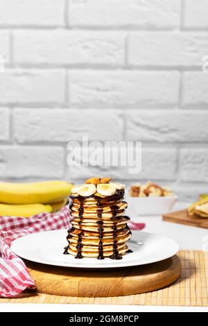 Pfannkuchen mit Schokoladensirup, Nüssen und Bananen. Stapel mit dem ganzen Flapjack. Leckeres Frühstück und gesundes Essen Stockfoto