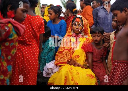 Mongla, Bangladesch. September 2021. Ein 14-jähriges Schulmädchen Hafsa sitzt mit Freunden und Nachbarn, während sie an ihrem Hochzeitstag in einem Dorf namens Joymoni aus einem Küstengebiet von Mongla im Bezirk Bagerhat für Fotos posiert.Bangladesch erlebte im vergangenen Jahr einen 13%igen Anstieg der Kinderheiraten während der Covid-19-Pandemie als die tödliche Das Virus hat Gesellschaften und Volkswirtschaften massiv getroffen und viele in extreme Armut getrieben. Die Abteilung für Geschlechtergerechtigkeit und Diversität von Brac, der weltweit größten NGO, fand heraus, dass die Kinderehe um 13 % gestiegen ist, als sie eine Umfrage durchführte, um auf die Auswirkungen der zuzugreifen Stockfoto