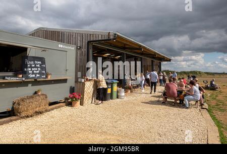 Chipping Norton, Oxfordshire, England, Großbritannien. 2021. Die Scheune und die Kunden essen und trinken von der Bar im Diddly Squat Farm Shop in der Nähe von Chipping Norton i Stockfoto