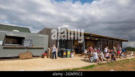 Chipping Norton, Oxfordshire, England, Großbritannien. 2021. Die Scheune und die Kunden essen und trinken von der Bar im Diddly Squat Farm Shop in der Nähe von Chipping Norton i Stockfoto