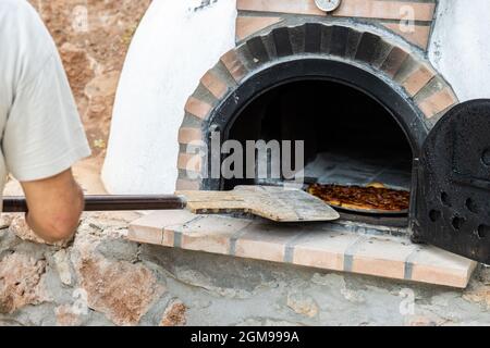 Pizza aus einem weiß lackierten, handgefertigten Holzofen, der auf der Außenseite gebaut wurde Stockfoto