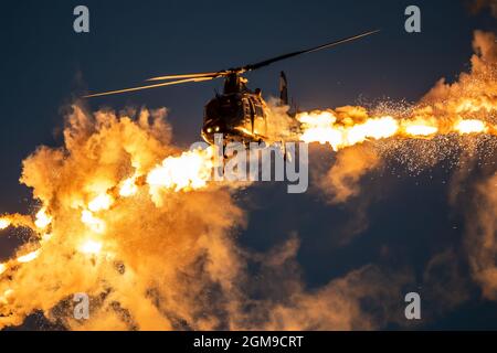 Armee Hubschrauber im Flug Abfeuern defensive Flare Köder in der Dämmerung. Stockfoto