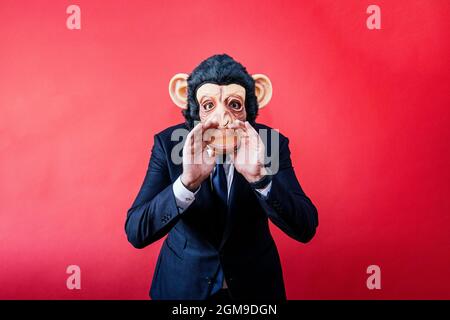 Geschäftsmann in Affenmaske, der mit den Händen auf dem Mund brüllt. Stockfoto