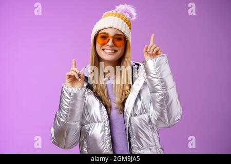 Freudig energetisiert unterhalten nette blonde Frau mit Spaß genießen Sie Urlaub Verschneite Bergtour trägt Sonnenbrille Silber Jacke Winter Hut tanzen Stockfoto