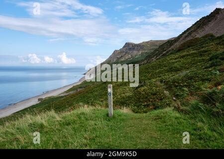 Eine Markierung des Wales Coast Path weist den Weg von Penrhyn Glas hinunter zum Strand von Porth y Nant mit Yr Eifl hinter der Lleyn Peninsula Stockfoto