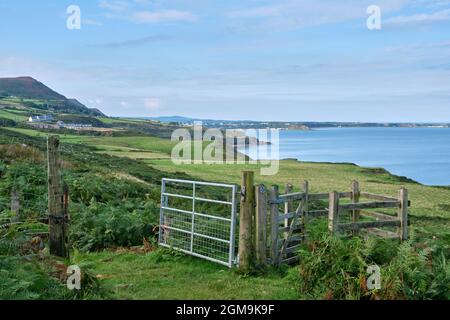 Ein Tor auf dem Wales Coast Path in der Nähe von Pistyll, das zu offenen Feldern mit Blick nach Westen entlang der zerklüfteten Nordküste der Lleyn Peninsula führt Stockfoto