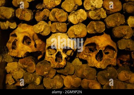 Unheimliche, gruselige menschliche Schädel und Knochen, die im unterirdischen Beinhaus gestapelt sind Stockfoto
