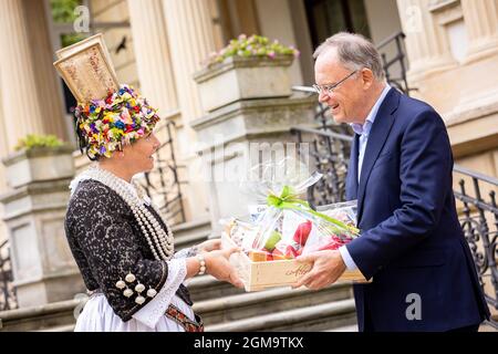 Hannover, Deutschland. September 2021. Marina Tajger, Altländer Blumenkönigin, überreicht Stephan weil (SPD), Ministerpräsident von Niedersachsen, bei einem Empfang für Ernte- und Produktkönige im Garten des Gästehauses der Niedersächsischen Landesregierung einen Geschenkkorb. Quelle: Moritz Frankenberg/dpa/Alamy Live News Stockfoto