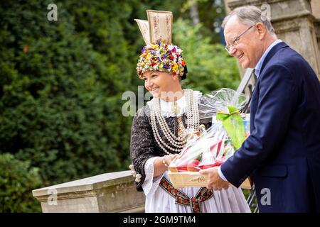 Hannover, Deutschland. September 2021. Marina Tajger, Altländer Blumenkönigin, überreicht Stephan weil (SPD), Ministerpräsident von Niedersachsen, bei einem Empfang für Ernte- und Produktkönige im Garten des Gästehauses der Niedersächsischen Landesregierung einen Geschenkkorb. Quelle: Moritz Frankenberg/dpa/Alamy Live News Stockfoto