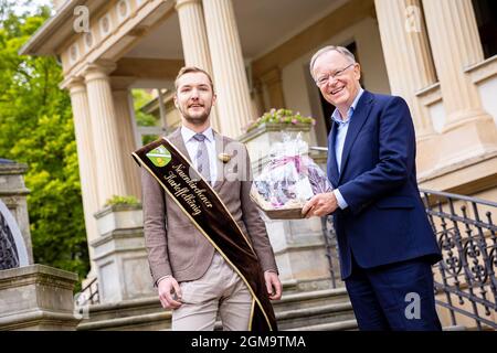 Hannover, Deutschland. September 2021. Julian Schäfer, Kartoffelkönig von Neuenkirchen, überreicht Stephan weil (SPD), Ministerpräsident von Niedersachsen, bei einem Empfang für Ernte- und Produktkönige und -Königinnen im Garten des Gästehauses der Niedersächsischen Landesregierung einen Geschenkkorb. Quelle: Moritz Frankenberg/dpa/Alamy Live News Stockfoto