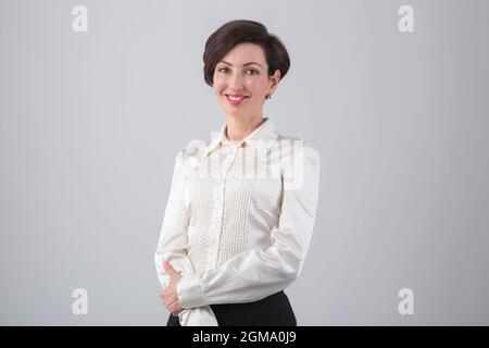 Junge Geschäftsfrau lächelt. Schöne Büroangestellte Frau in den 40er Jahren trägt klassisches formelles Hemd und roten Lippenstift posiert im Studio Stockfoto
